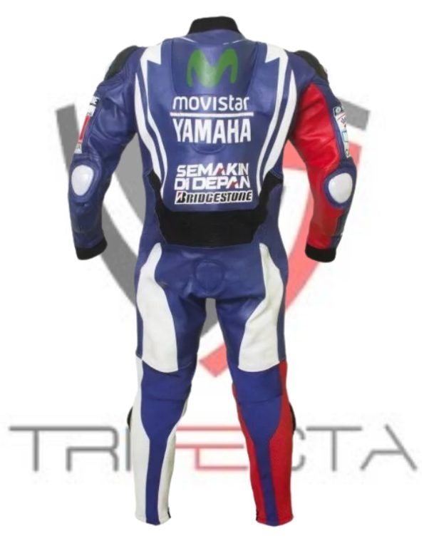 A motorcycle racing suit standing against a white background with the logo ‘TRIFECTA’ at the bottom. The suit is predominantly blue with white and red accents, featuring several logos from sponsors such as ‘Movistar,’ ‘Yamaha,’ ‘Semakin Di Depan,’ and ‘Bridgestone.’ The design of the suit suggests it is meant for professional racing, given the placement of sponsor logos and protective elements typical of high-speed motorcycle racing gear